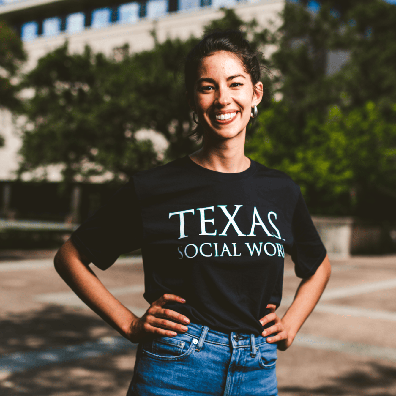 A UT student with a shirt that says Texas Social Work, standing outside.